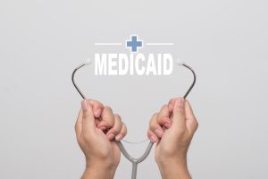 Hands holding a stethoscope and word "MEDICAID" medical concept.