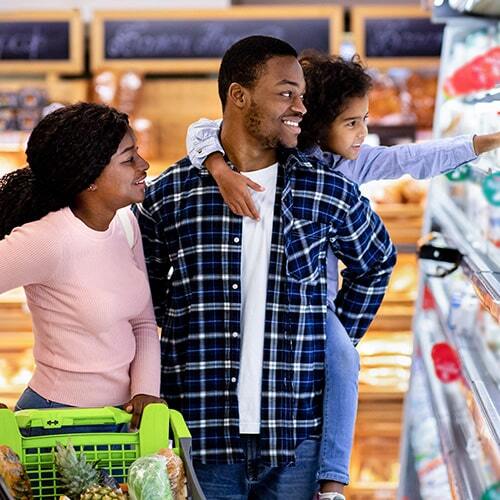 A happy African American family with shopping cart, shopping together at a grocery store.